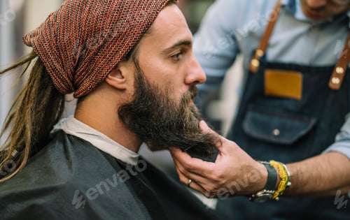 Preview: Man arranging his beard in modern barbershop.