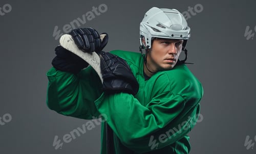 Preview: Hockey player wearing black protective uniform holds a hockey stick on a gray background.