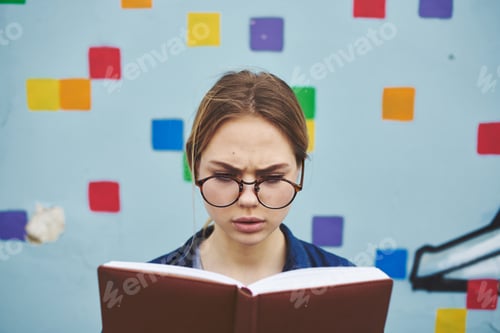 Preview: Surprised female student in glasses on the street with a book of emotions model