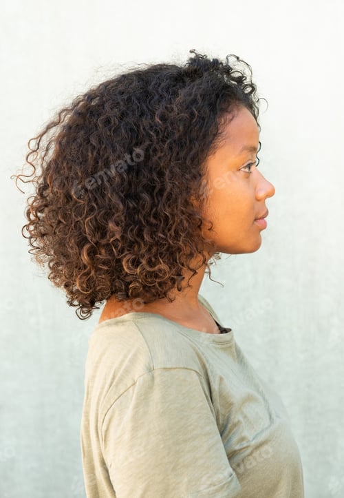 Preview: Side of young African American woman with curly hair against green background