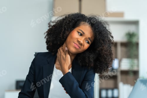 Preview: A young African American woman with Afro brown hair in a modern office experiencing office syndrome