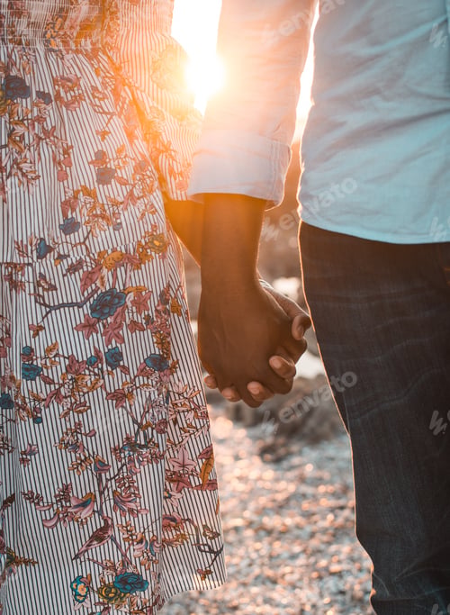 Preview: Young couple holding hand at sunset at the beach
