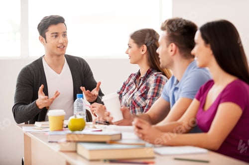 Preview: Cheerful students. Four cheerful students talking to each other while sitting at the desk