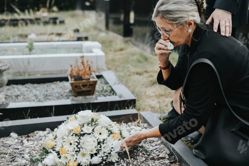 Preview: Old woman laying flowers on a grave