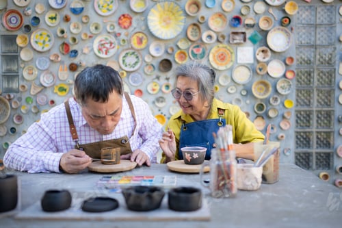 Preview: Asian retired couple is engaged in pottery making and clay painting activities.
