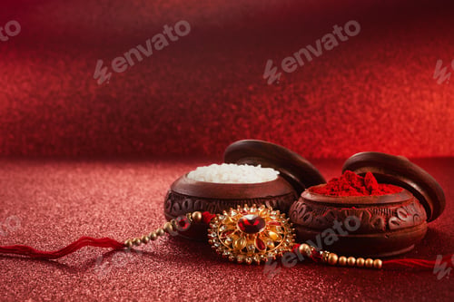 Preview: Raksha Bandhan. Rakhi string, Rice Grains and Kumkum on red background.