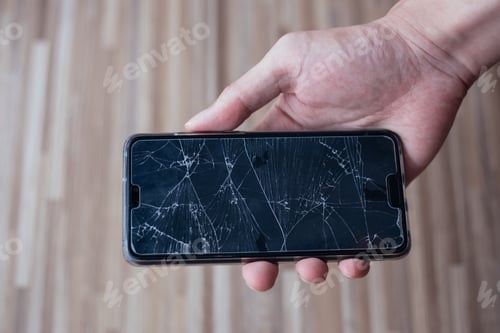 Preview: Close-up of human hand holding a broken and damaged glass of mobile phone from accident.