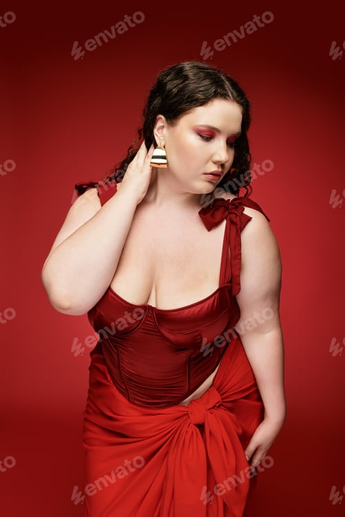 Preview: Stylish young woman in red dress poses elegantly against a bold red backdrop