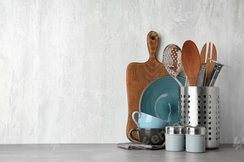 Preview: Different kitchen utensils on grey table against light background. Space for text