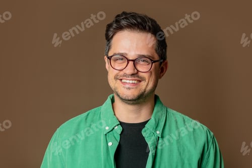 Preview: Stylish caucasian man in glasses and green shirt on brown background