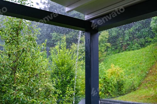 Preview: Streams of rainwater pour down the roof gutters onto a porch.