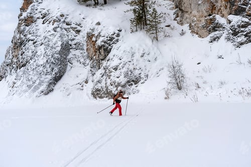 Preview: Young man with backpack skiing near rocks, winter sport and hiking, active lifestyle, in nature