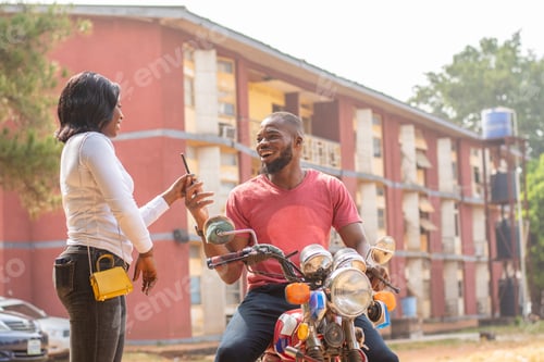 Preview: african lady hands her phone to a bike man