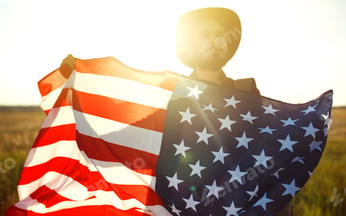 Preview: 4th of July. American Flag. Traveler with the flag of America. The man in a hat, a backpack.