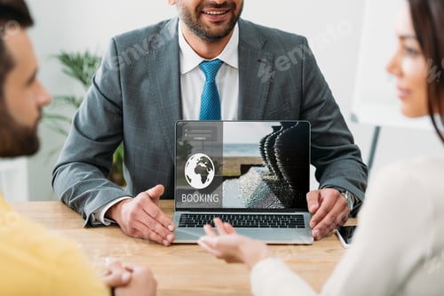 Preview: cropped view of advisor sitting at table and laptop with booking website on screen with investors in