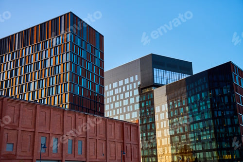 Preview: Modern glass office buildings reflecting city skyline at sunset