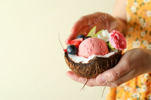Preview: Woman holds coconut with fruit ice cream, close up