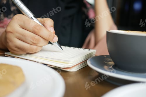 Preview: Close up of women hand writing on notepad.