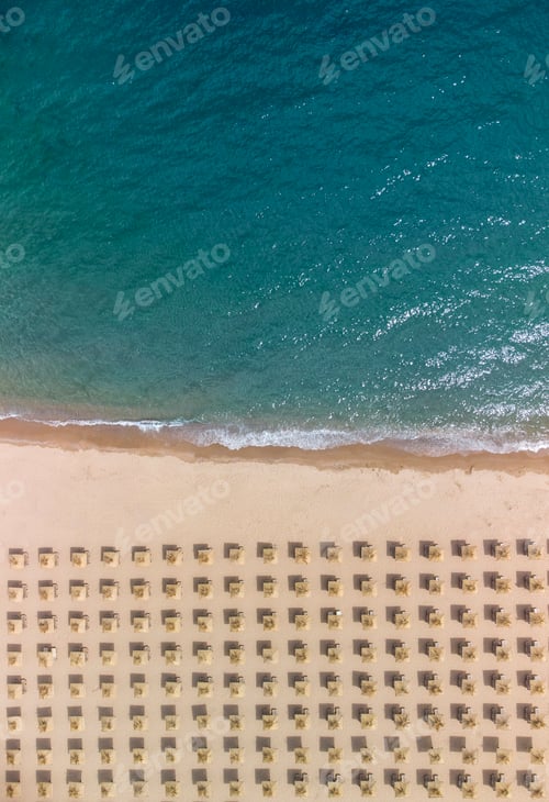 Preview: Aerial view of an amazing empty sand beach with straw beach umbrellas and turquoise clear water.
