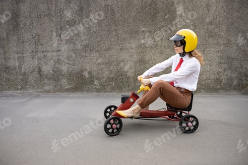 Preview: Funny businesswoman driving retro pedal car outdoor