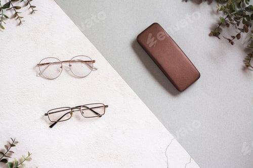 Preview: A pair of metal-framed glasses and a case on a two-tone background.
