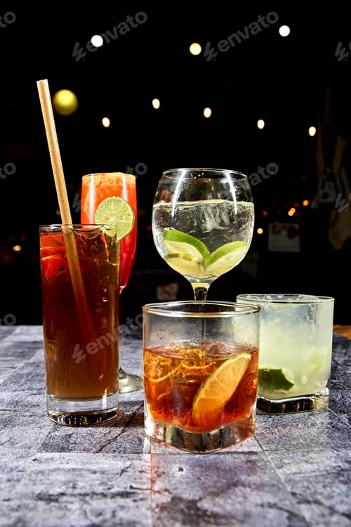 Preview: Selective focus shot of cocktails in transparent glasses with ice cubes, lemon, bokeh background