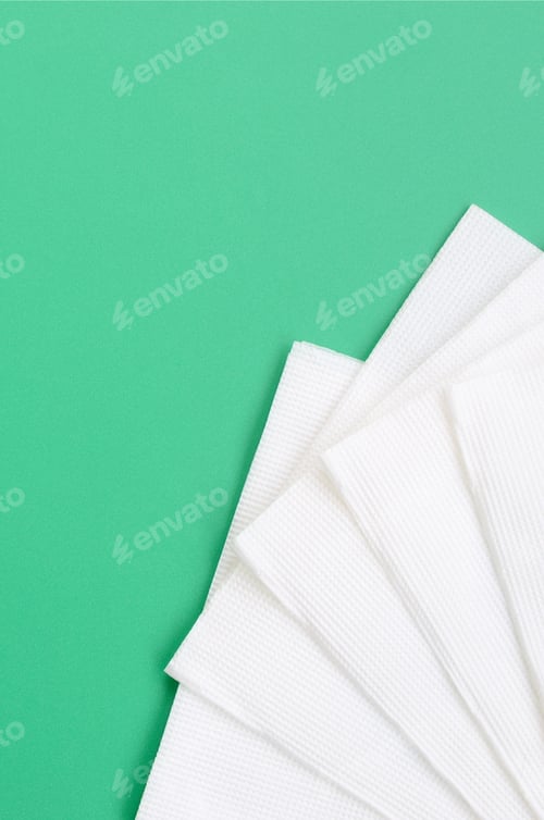 Preview: Several white paper napkins lie on a plastic green background