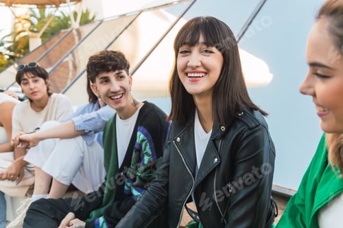 Preview: Happy young ethnic woman sitting with friends on building roof in daylight