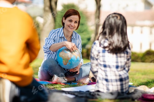 Preview: Teacher with small children sitting outdoors in city park, learning group education concept