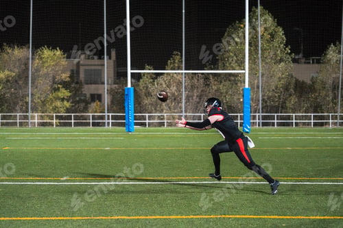 Preview: American football player catching ball on field at night