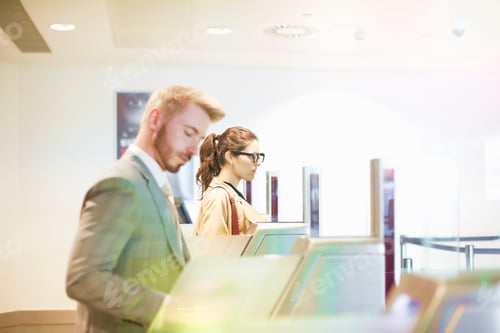 Preview: Businessman and woman walking through security gate at airport, side view