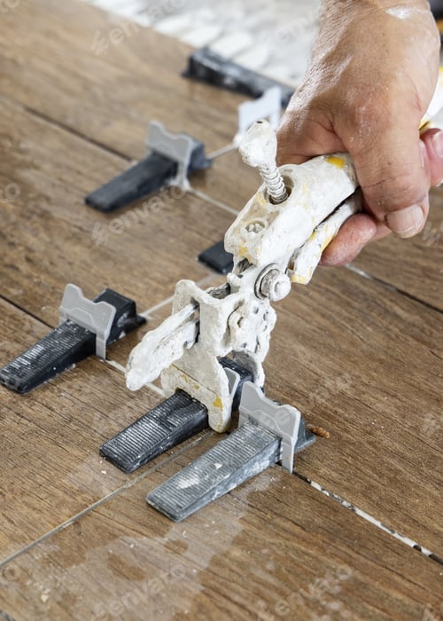 Preview: Craftsman using tile leveling system during tiling a floor, hand closeup. Construction of building