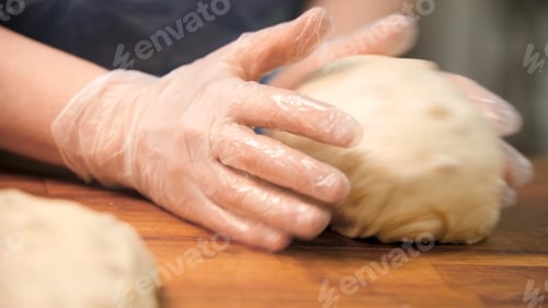 Preview: Woman in cooking gloves kneading dough on wooden board, food preparation concept. Stock footage