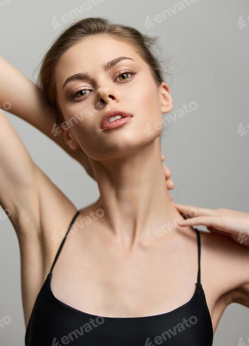 Preview: Young Caucasian woman posing gracefully with one arm behind her head, showcasing confidence and