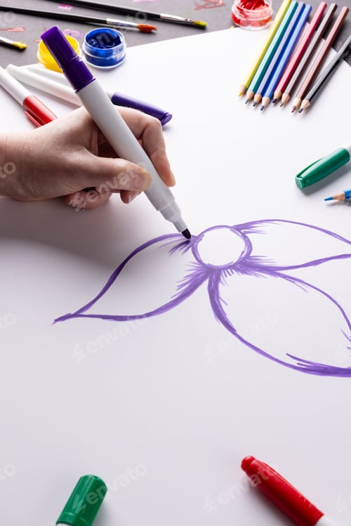 Preview: Vertical image of hand drawing purple flower on paper and art materials on table top, copy space