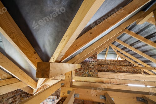 Preview: Attic of a building under construction with wooden beams of a roof structure and brick walls