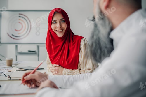 Preview: Muslim businesswoman smiling at colleague during meeting in office