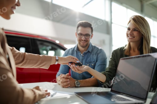Preview: Female customer receiving car keys, shaking hands with saleswoman.