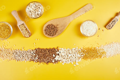 Preview: Flat lay of set of heap various grains and cereals on yellow background