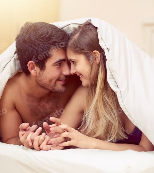 Preview: Shot of a loving young couple smiling at each other while lying under a blanket together