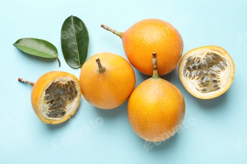 Preview: Ripe yellow passion fruits and leaves on light blue background, flat lay