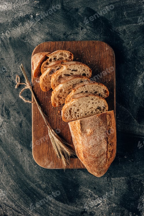 Preview: top view of arranged pieces of bread on cutting board on dark surface with flour