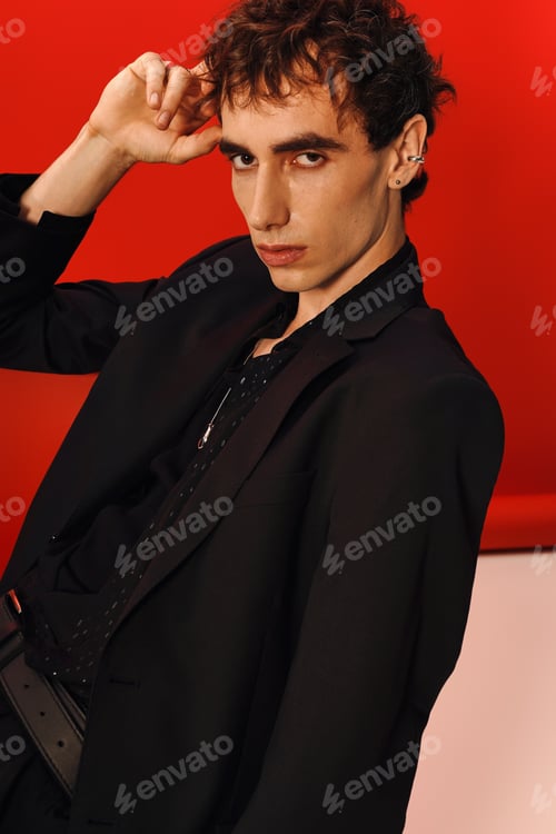 Preview: Stylish man showcases elegant fashion against a bold red backdrop in a modern setting