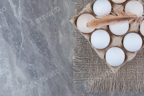 Preview: Cardboard box with white chicken eggs and feather