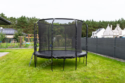 Preview: Large childrens jumping trampoline with protective net and closed zipper, visible mesh masking.