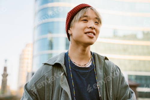 Preview: Asian happy boy wearing hat laughing while walking at city street