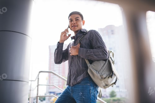 Preview: Millennial guy use smartphone and go up on stairs
