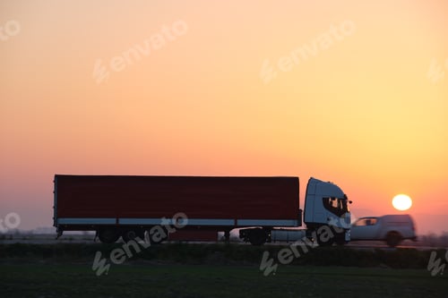 Preview: Semi-truck with cargo trailer driving on highway hauling goods in evening.