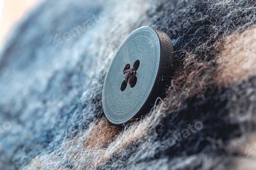 Preview: Button on a warm blue shirt, macro shot.