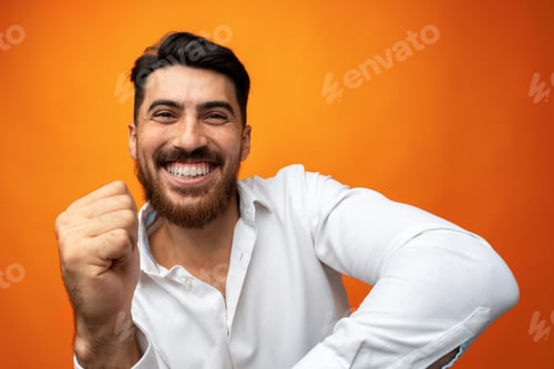 Vista previa: Young man celebrating and dancing against orange background in studio